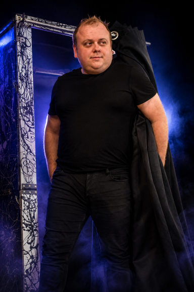 Odeeni Circus of Illusion magician standing beside a stage illusion prop.
