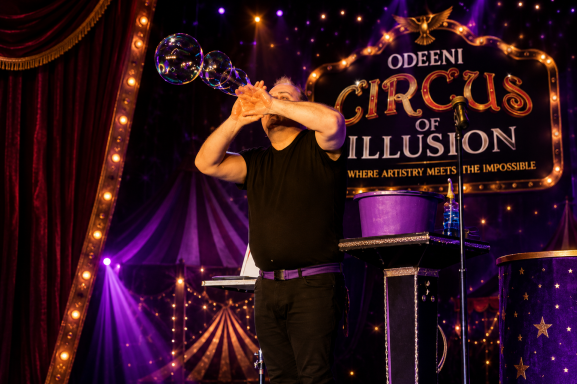 Odeeni Circus of Illusion performer creating giant bubbles during a colourful live circus show.