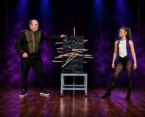 Odeeni Circus of Illusion magician and assistant performing a dramatic sword penetration stage illusion.